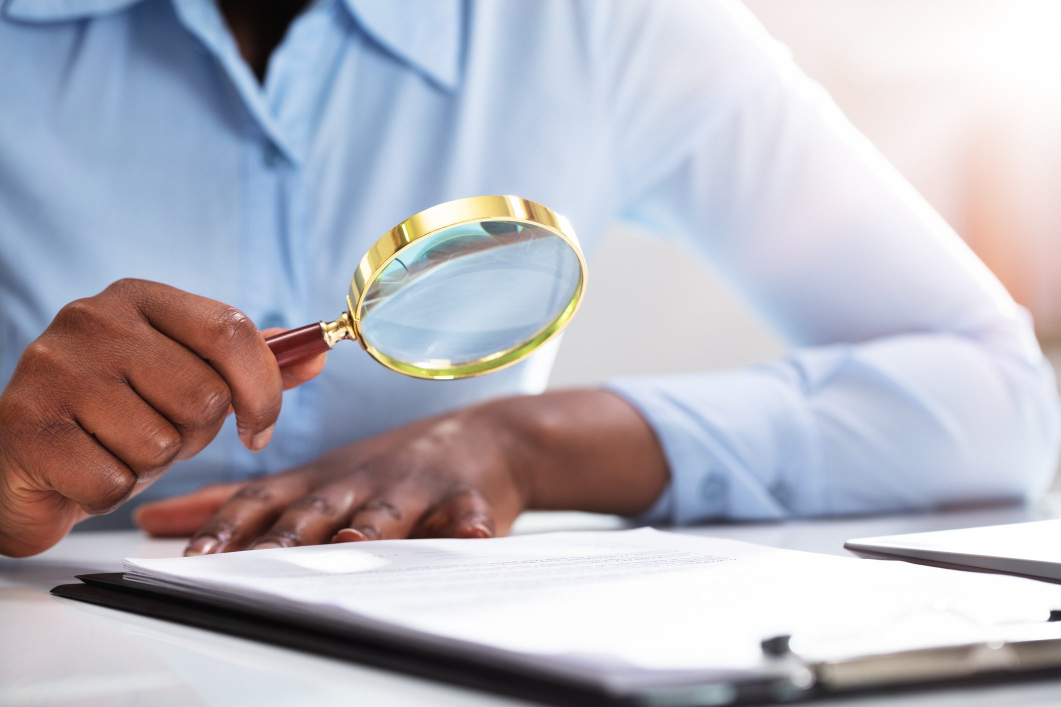 Businessperson Looking At Contract Form Through Magnifying Glass